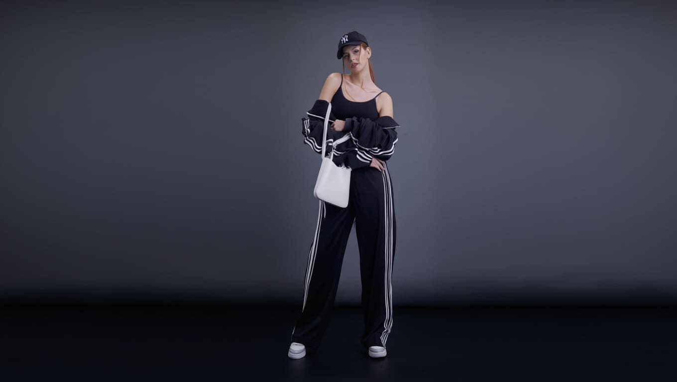 Mulher elegante usando look street chic preto com calça wide leg, cropped e bolsa branca estruturada em estilo luxo acessível